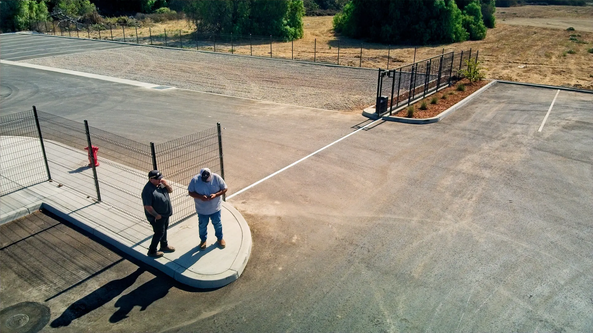 Good Neighbor Fence team on site beside a newly installed black steel fence and gate at a commercial lot