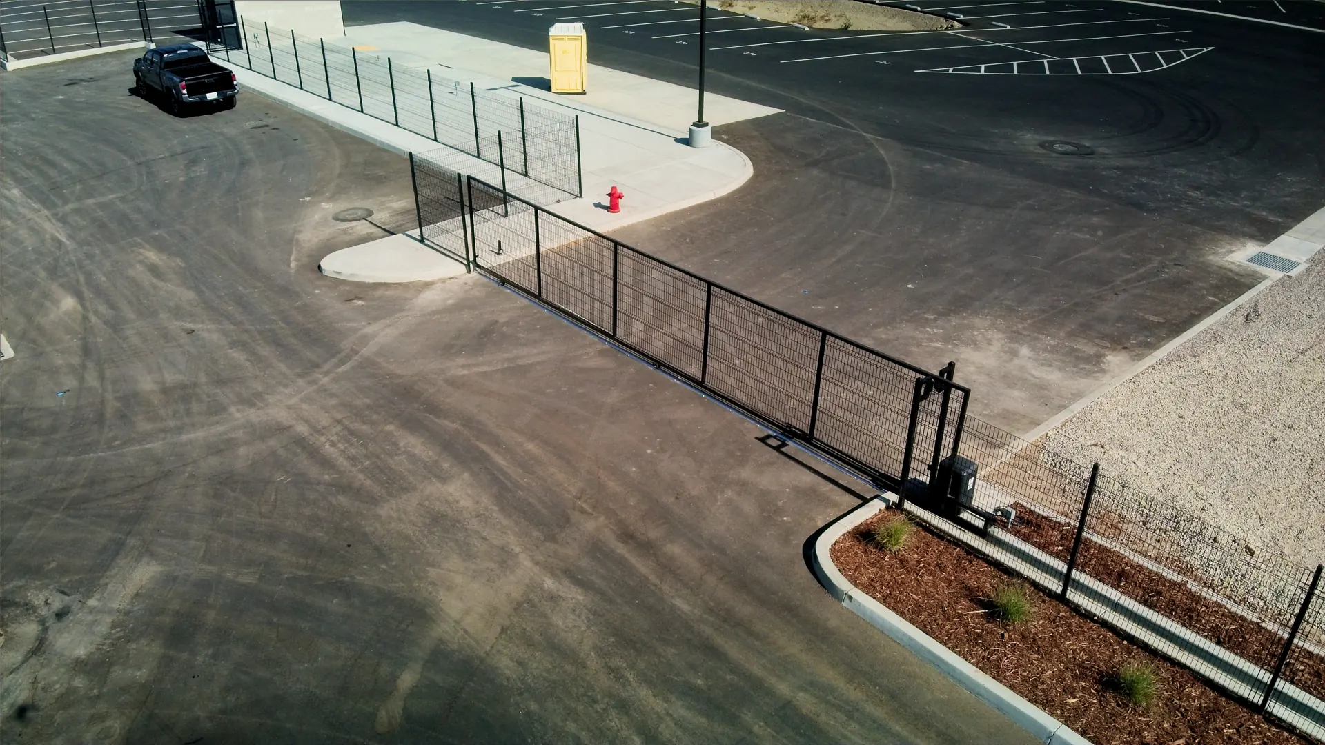 Aerial angle of a steel fence and rolling gate following a curved curb