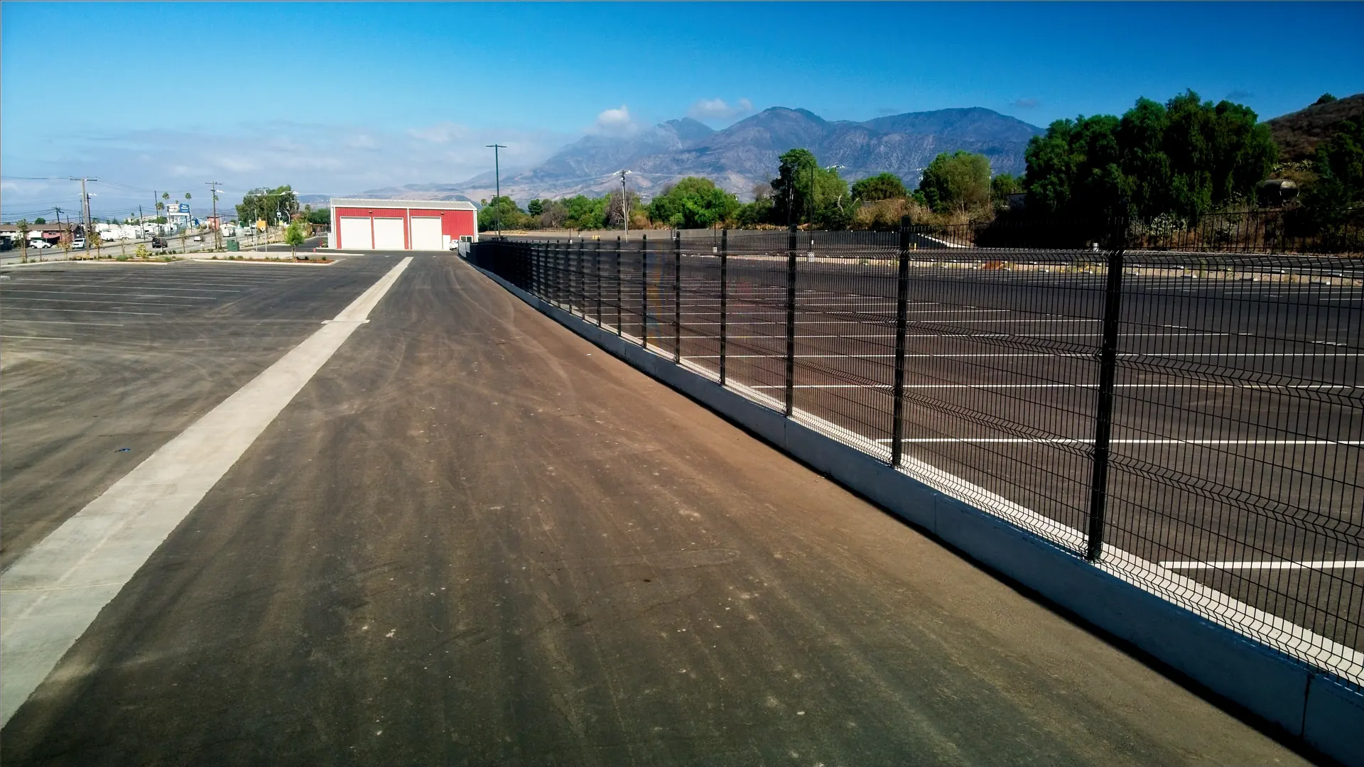 Long run of black steel panel fencing on a concrete curb with mountains behind