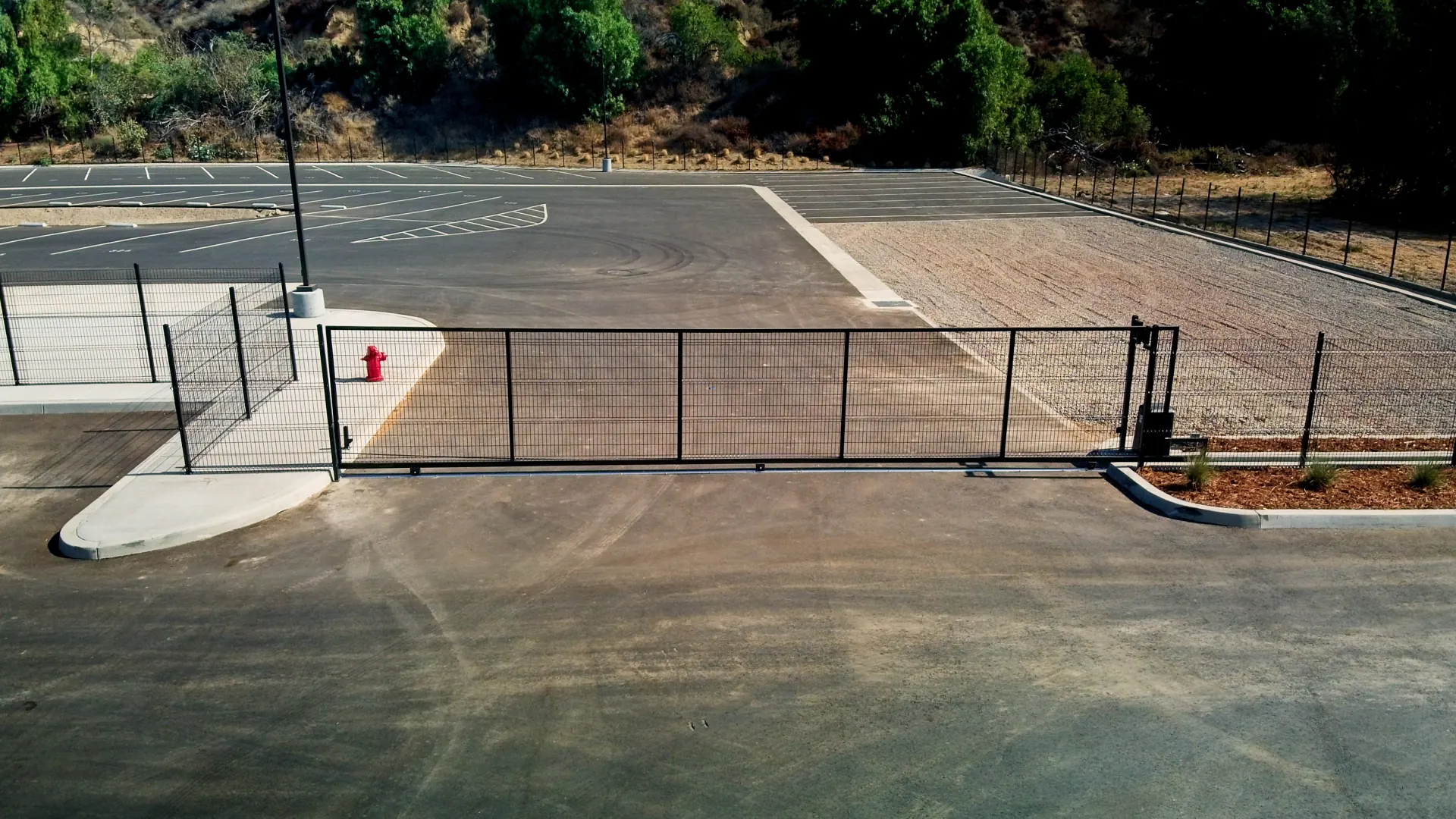 Front view of a black steel rolling gate across a lot entrance