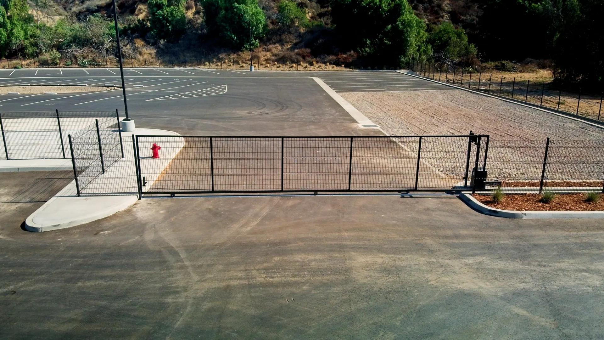 Black rolling vehicle gate closing off a commercial parking area